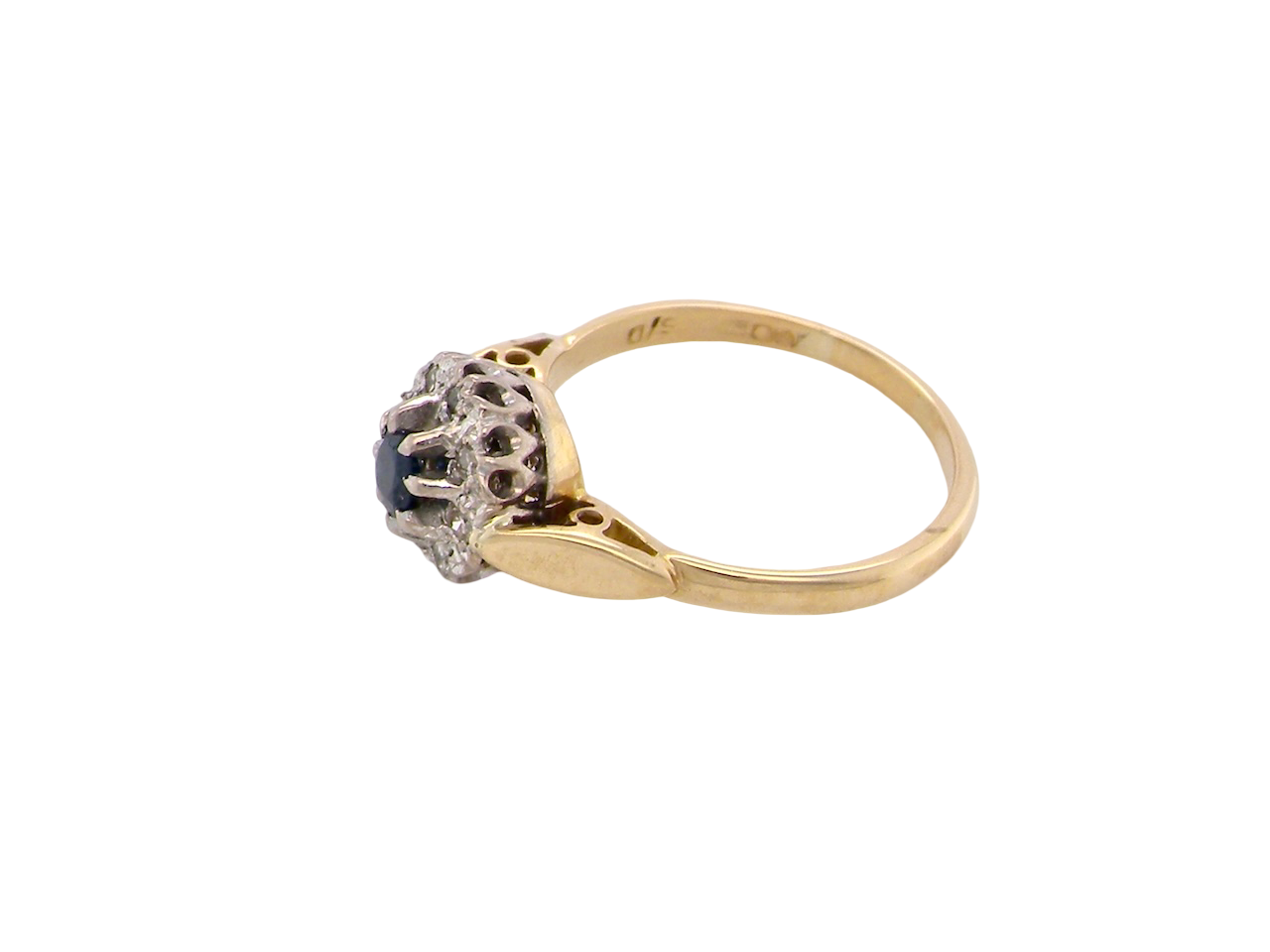 side An 18 carat gold cluster ring, features to the centre a dark blue sapphire, 3.6mm diameter. Claw set.