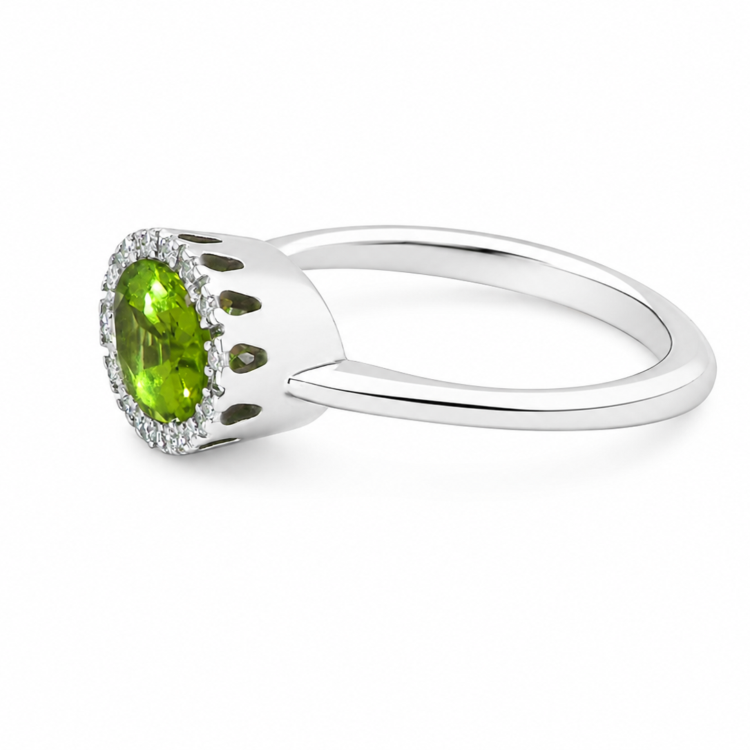 side An 18 carat white gold* cluster ring. Features and oval shaped peridot gemstone, measures 8.5x6.5mm.