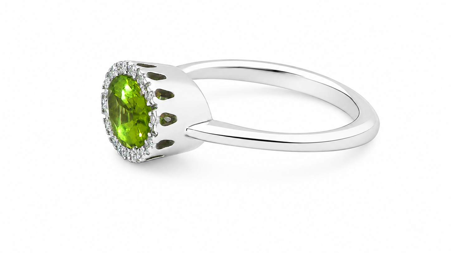 side An 18 carat white gold* cluster ring. Features and oval shaped peridot gemstone, measures 8.5x6.5mm.