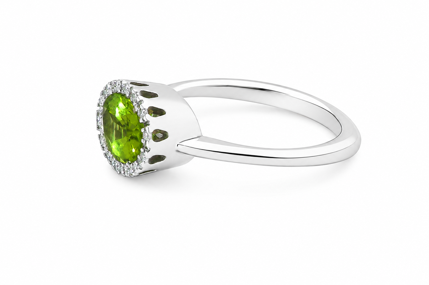 side An 18 carat white gold* cluster ring. Features and oval shaped peridot gemstone, measures 8.5x6.5mm.