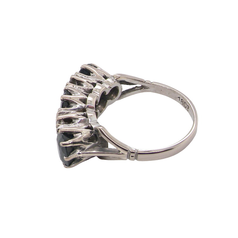 A vintage-style ring featuring a cluster of dark, round gemstones in a prong setting, shown on a plain white background.