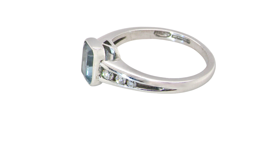 side An 18 carat white gold ring, features a rectangular step cut aquamarine, measures 7x5mm (st one carat) sky blue, fine clarity. Rim setting.