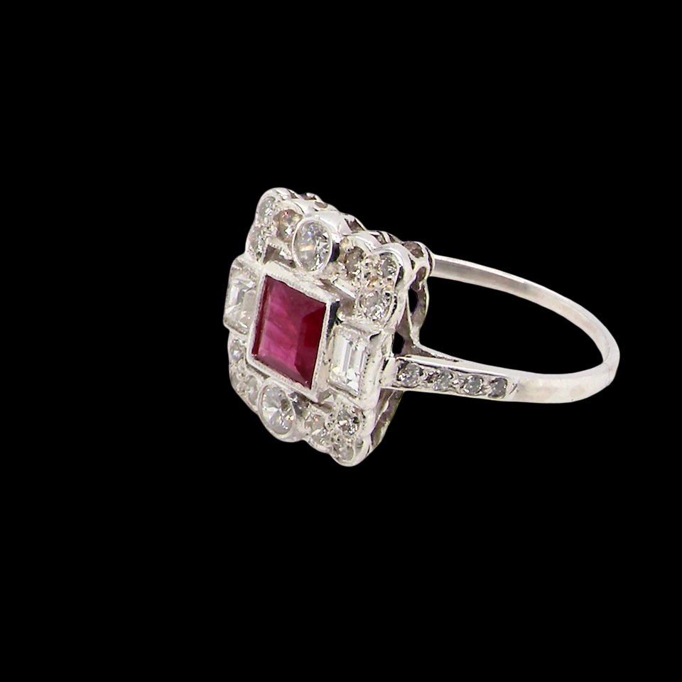 side An Art Deco style cluster ring. Set to the centre a square 5x5mm ruby, rub over setting and complimented by a surround of mixed cut white diamonds.