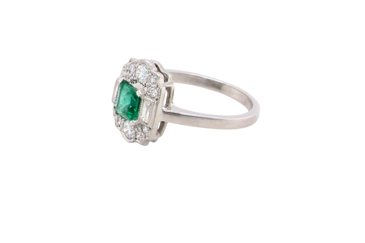 side An elegant Art Deco–style cluster ring of plaque design, centred with a square step-cut emerald measuring approximately 4.5 × 4.5 mm (estimated 0.40 carats). The emerald displays a vibrant, lively green colour and is beautifully framed by diamonds.