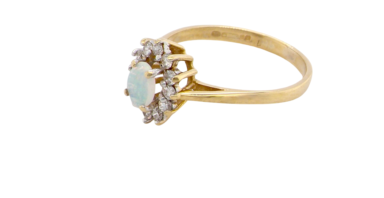 side An elegant cluster ring featuring a white opal centre stone measuring 6 × 4mm, displaying a lively and attractive play of colour.