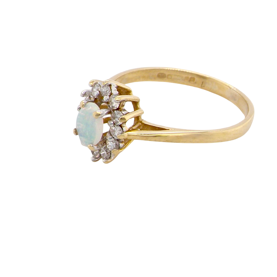 side An elegant cluster ring featuring a white opal centre stone measuring 6 × 4mm, displaying a lively and attractive play of colour.