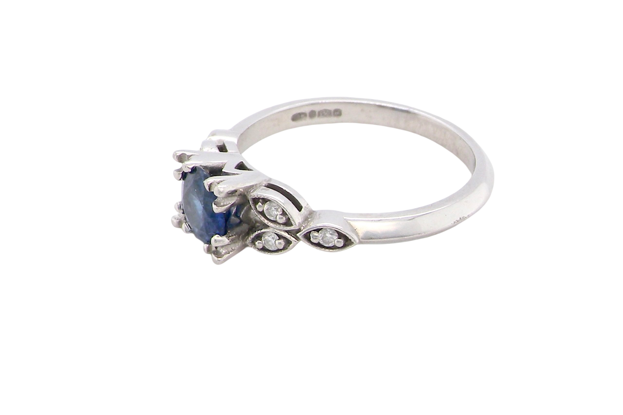 side An elegant vintage-style platinum ring showcasing a beautifully proportioned round sapphire with a soft mid to light cornflower blue hue. The sapphire measures 5.6mm in diameter (approx. 0.80 carats)