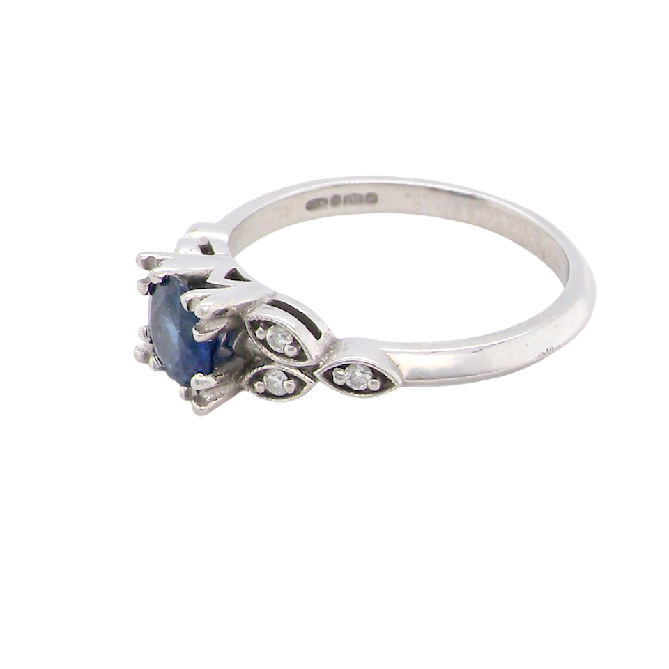 side An elegant vintage-style platinum ring showcasing a beautifully proportioned round sapphire with a soft mid to light cornflower blue hue. The sapphire measures 5.6mm in diameter (approx. 0.80 carats)