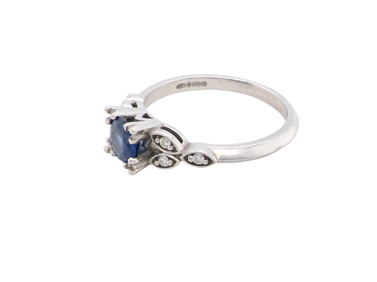 side An elegant vintage-style platinum ring showcasing a beautifully proportioned round sapphire with a soft mid to light cornflower blue hue. The sapphire measures 5.6mm in diameter (approx. 0.80 carats)