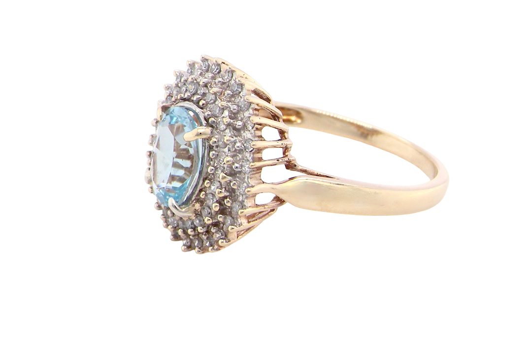 side An impressive cluster ring that features to the centre an oval cut blue topaz gemstone, 8x6mm sky blue colour.
Complimented by an outer double halo of diamonds
