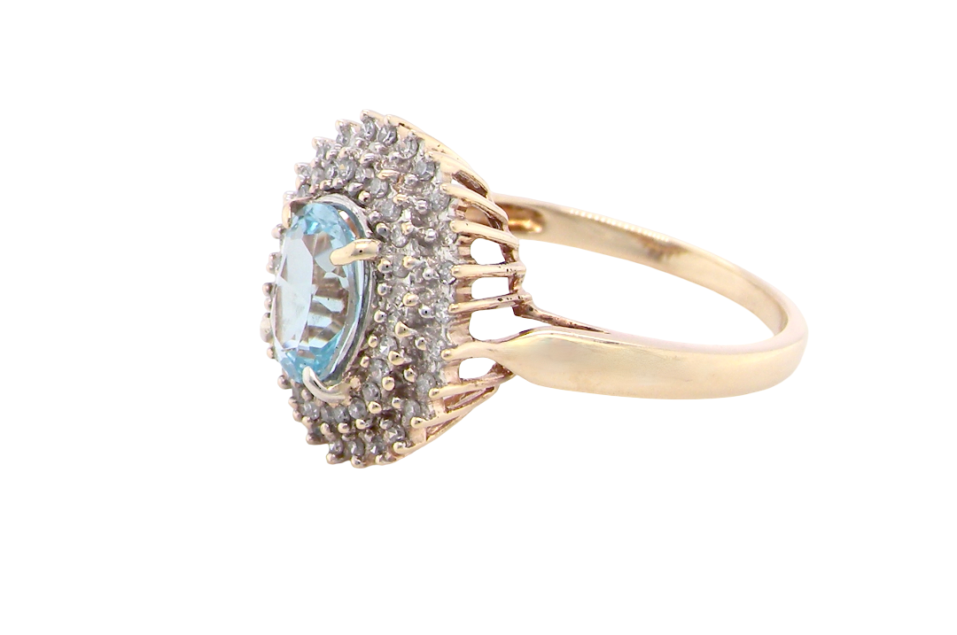 side An impressive cluster ring that features to the centre an oval cut blue topaz gemstone, 8x6mm sky blue colour.
Complimented by an outer double halo of diamonds