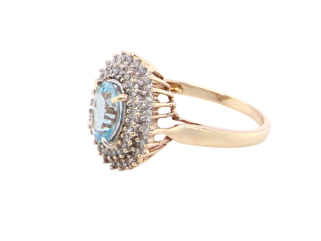 side An impressive cluster ring that features to the centre an oval cut blue topaz gemstone, 8x6mm sky blue colour.
Complimented by an outer double halo of diamonds