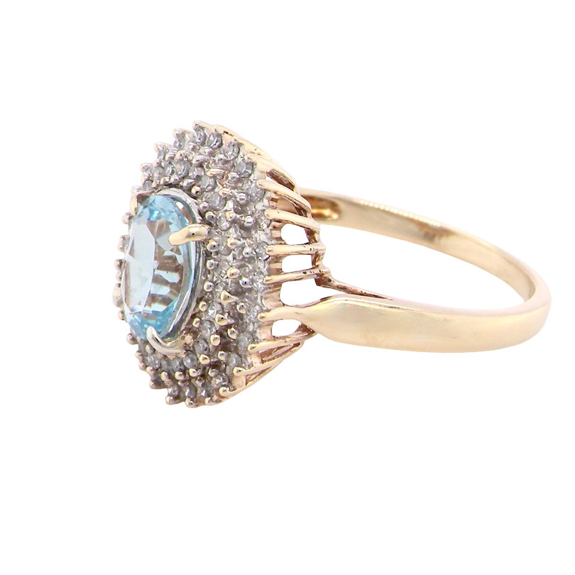 side An impressive cluster ring that features to the centre an oval cut blue topaz gemstone, 8x6mm sky blue colour.
Complimented by an outer double halo of diamonds