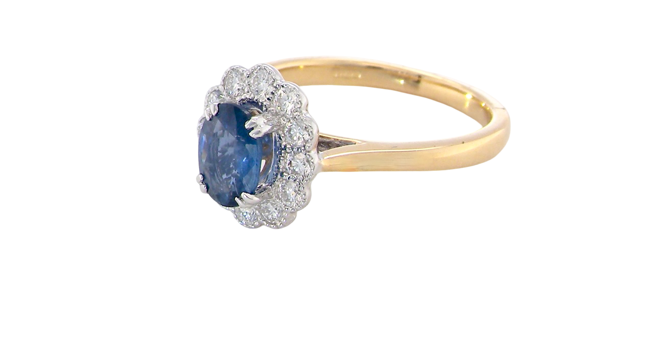 side A cluster ring featuring an oval-cut mid to dark blue sapphire measuring 7 × 5 mm (approximately ¾ carat).