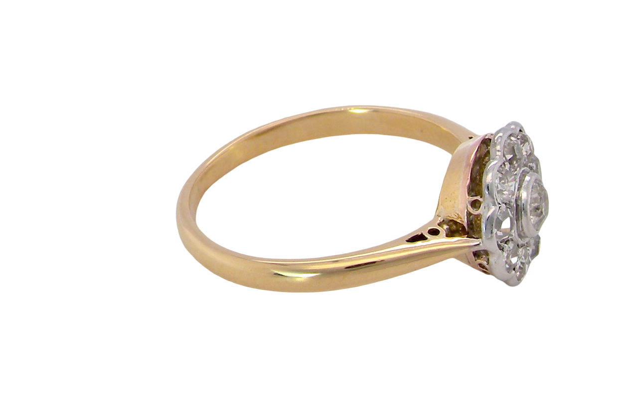 side early 20th-century vintage diamond cluster ring, featuring a classic daisy-shaped head set with nine old brilliant-cut white diamonds.
