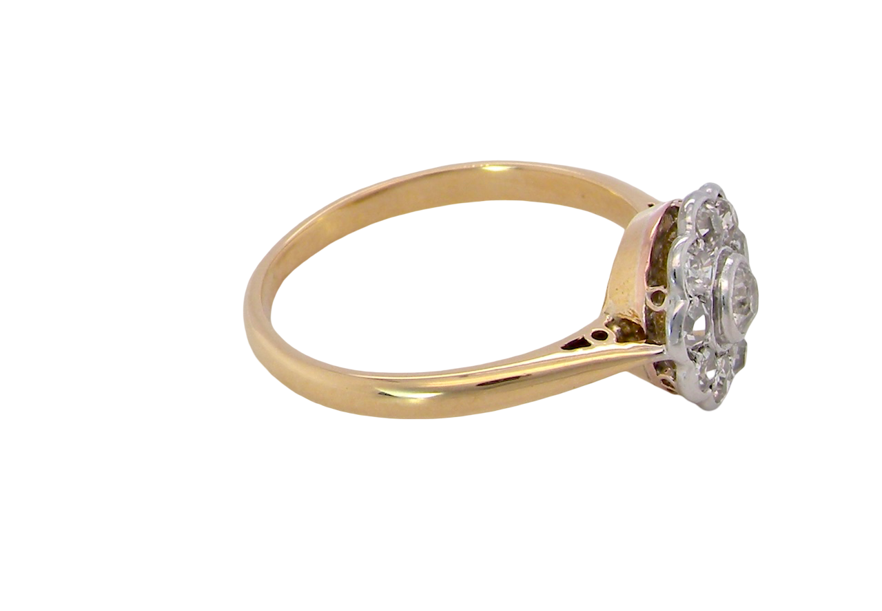 side early 20th-century vintage diamond cluster ring, featuring a classic daisy-shaped head set with nine old brilliant-cut white diamonds.
