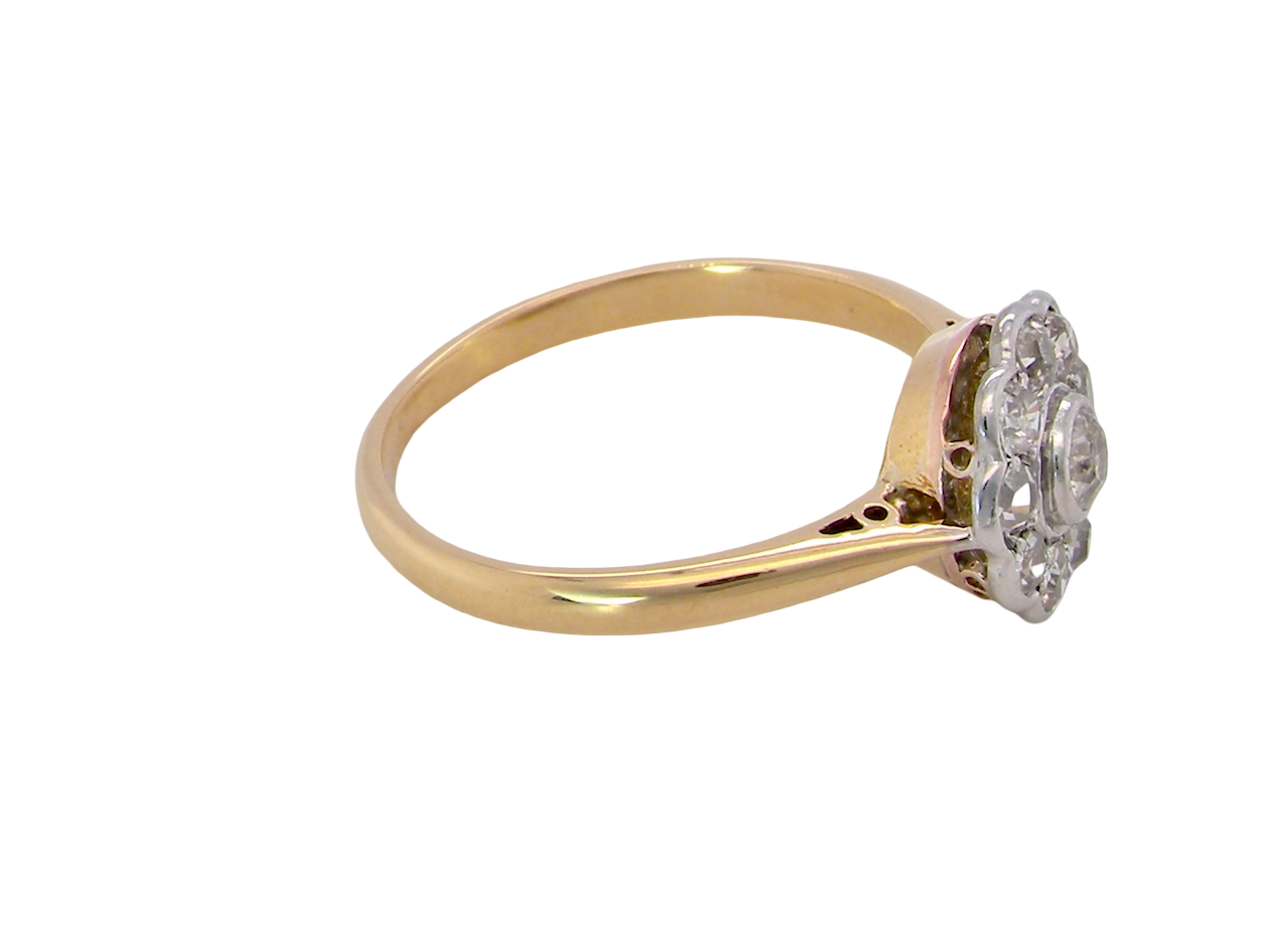 side early 20th-century vintage diamond cluster ring, featuring a classic daisy-shaped head set with nine old brilliant-cut white diamonds.