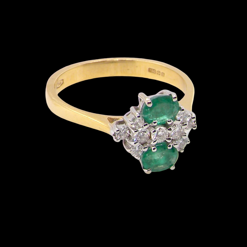 Gold ring with emerald and diamonds on a black background