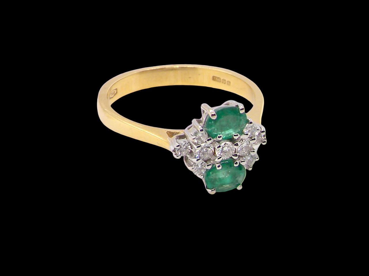 Gold ring with emerald and diamonds on a black background