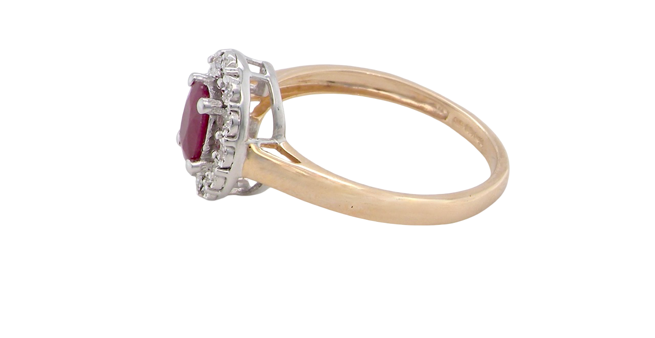 side oval ruby measuring 6x4mm (approx. 0.44 carats) in a raspberry red hue. The centre stone is accented by a halo of twelve white diamonds