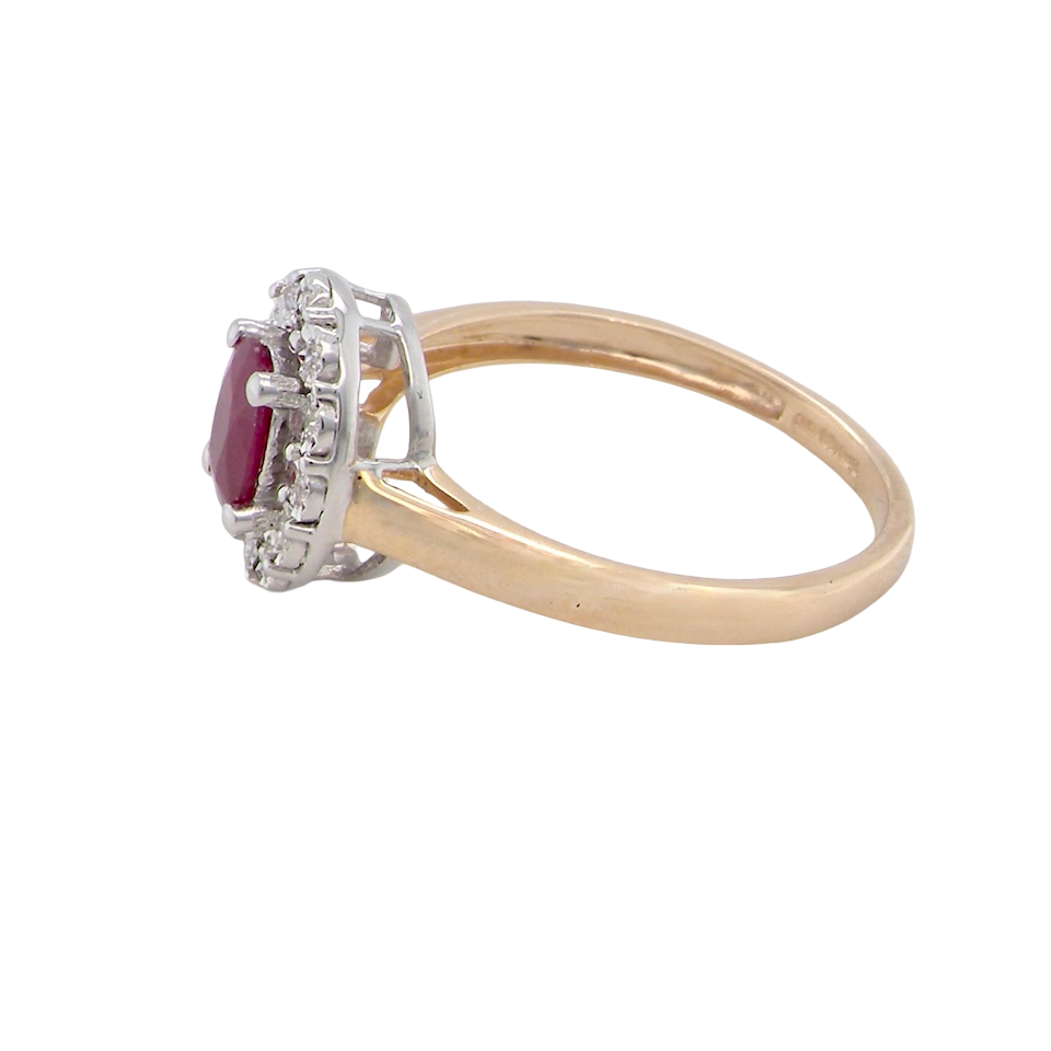 side oval ruby measuring 6x4mm (approx. 0.44 carats) in a raspberry red hue. The centre stone is accented by a halo of twelve white diamonds