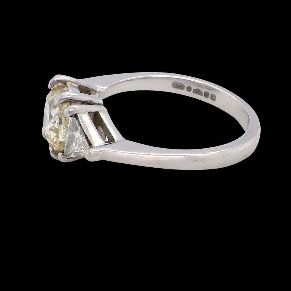 side striking and elegant trilogy ring crafted in 18-carat white gold, set with a vibrant fancy yellow cushion-cut diamond