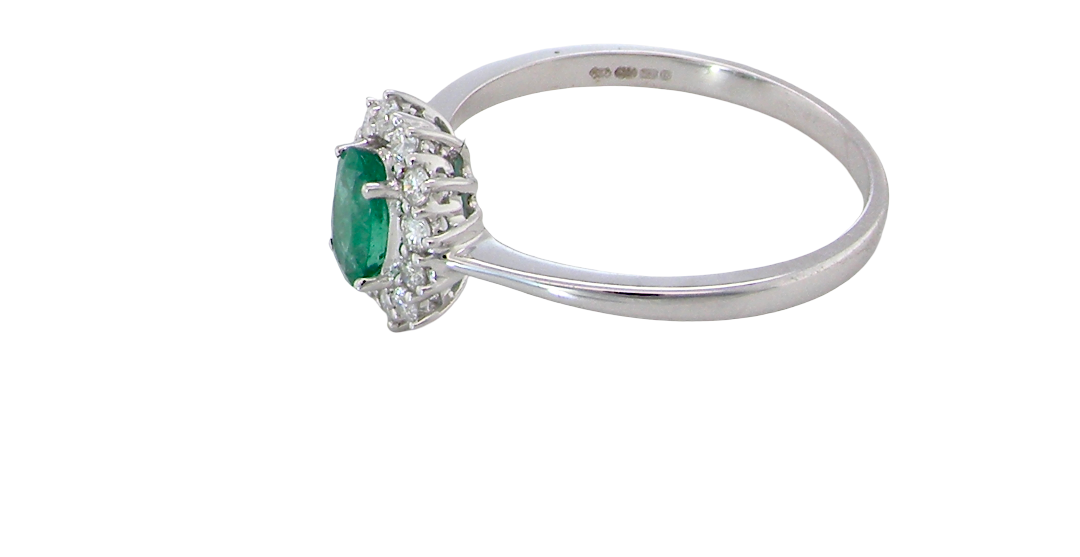 side A classic cluster ring set with an oval cut emerald centre stone, measures 6x4mm, grass green colour.
Complimented by an outer halo of twelve brilliant cut white diamonds, each 1.7mm (total est at 0.25 carats)