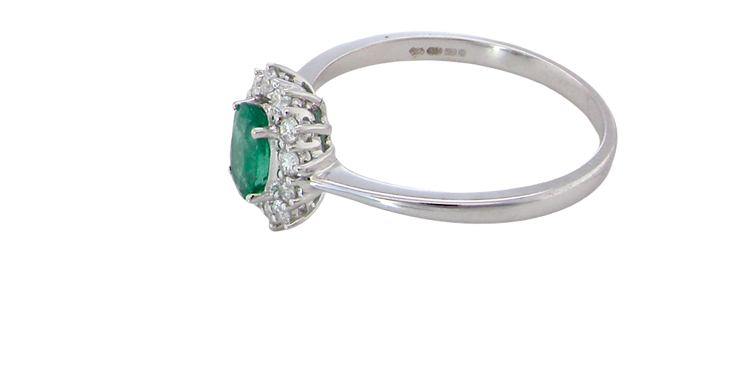 side A classic cluster ring set with an oval cut emerald centre stone, measures 6x4mm, grass green colour.
Complimented by an outer halo of twelve brilliant cut white diamonds, each 1.7mm (total est at 0.25 carats)