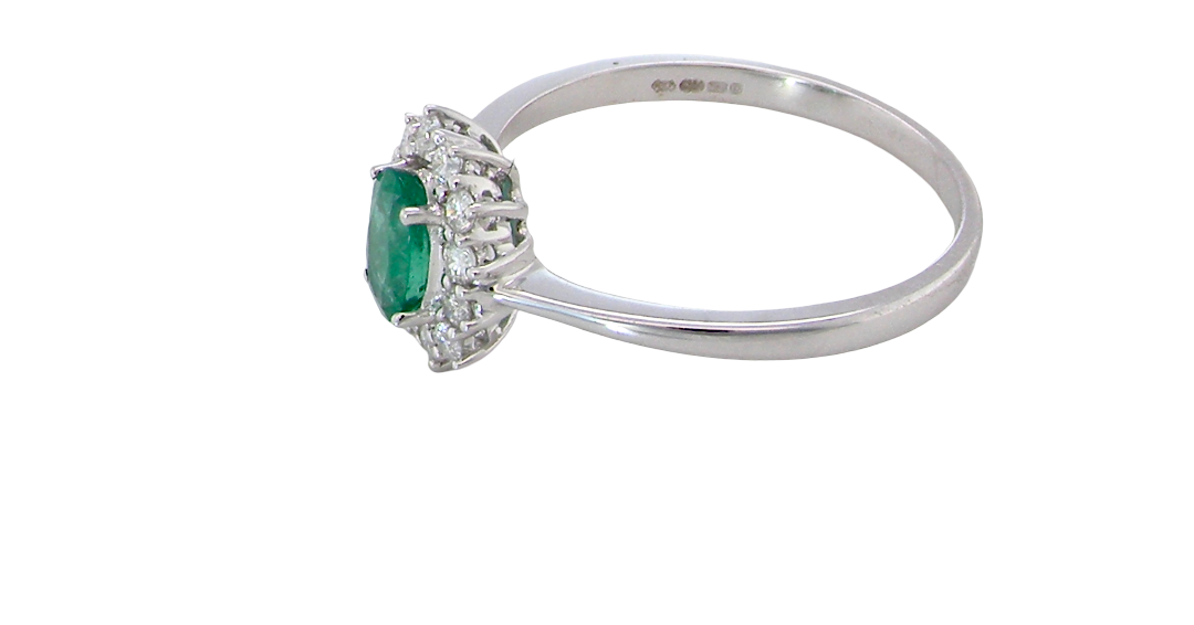 side A classic cluster ring set with an oval cut emerald centre stone, measures 6x4mm, grass green colour.
Complimented by an outer halo of twelve brilliant cut white diamonds, each 1.7mm (total est at 0.25 carats)