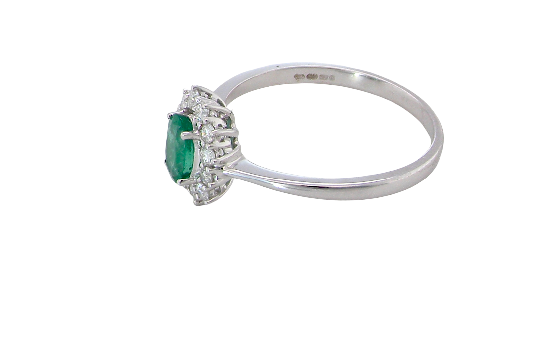 side A classic cluster ring set with an oval cut emerald centre stone, measures 6x4mm, grass green colour.
Complimented by an outer halo of twelve brilliant cut white diamonds, each 1.7mm (total est at 0.25 carats)