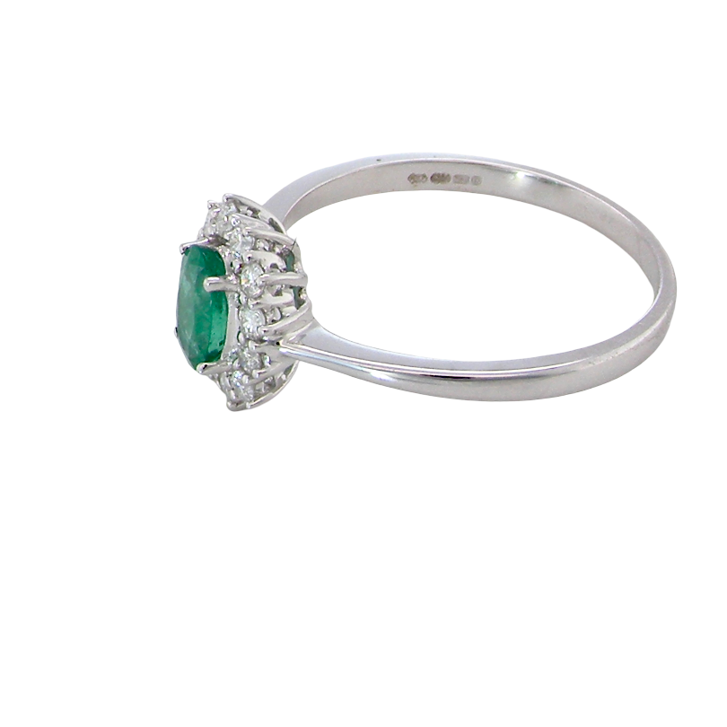 side A classic cluster ring set with an oval cut emerald centre stone, measures 6x4mm, grass green colour.
Complimented by an outer halo of twelve brilliant cut white diamonds, each 1.7mm (total est at 0.25 carats)