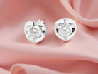 Heart-shaped diamond earrings on a soft pink background
