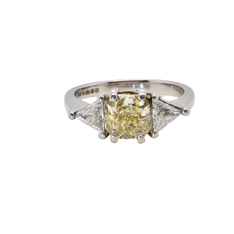 striking and elegant trilogy ring crafted in 18-carat white gold, set with a vibrant fancy yellow cushion-cut diamond
