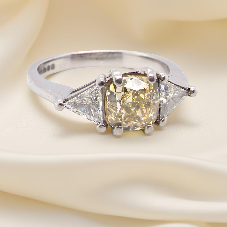 striking and elegant trilogy ring crafted in 18-carat white gold, set with a vibrant fancy yellow diamond