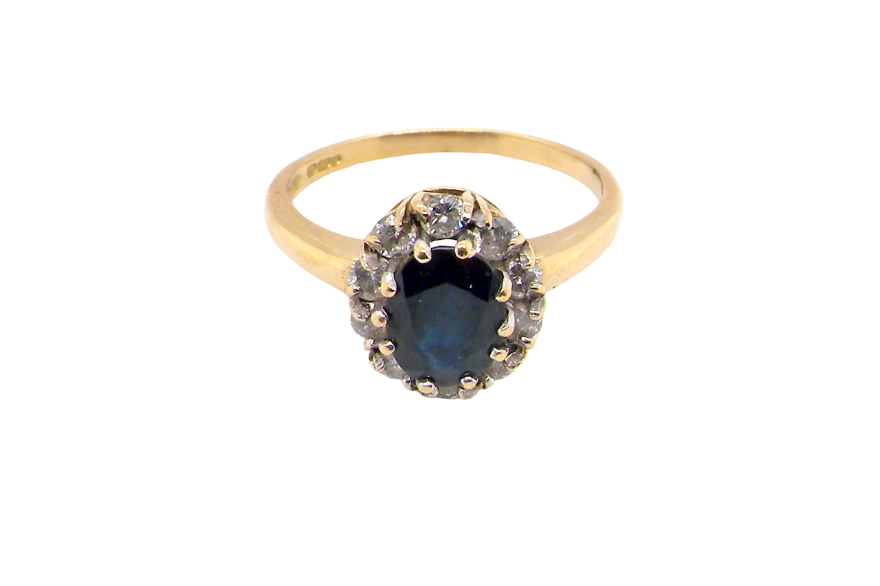 top An elegant 18 carat gold cluster ring featuring a striking inky dark blue sapphire at its centre.
