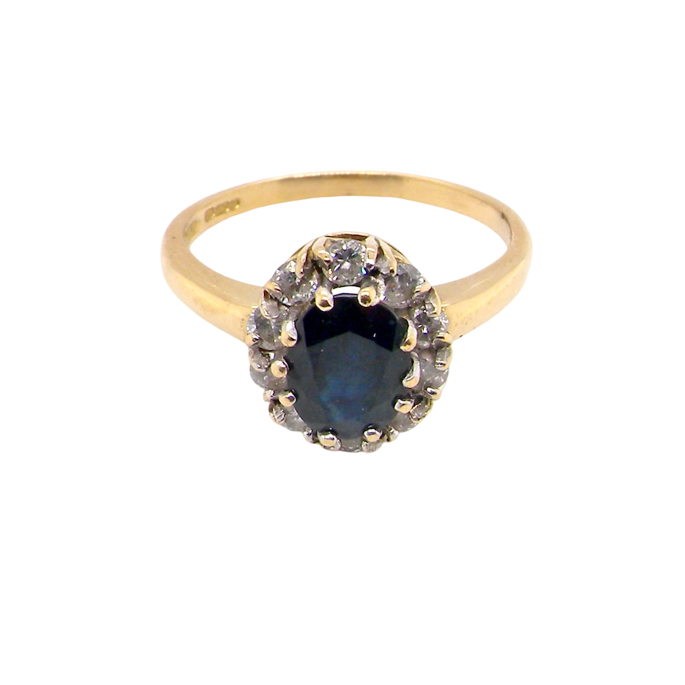 top An elegant 18 carat gold cluster ring featuring a striking inky dark blue sapphire at its centre.