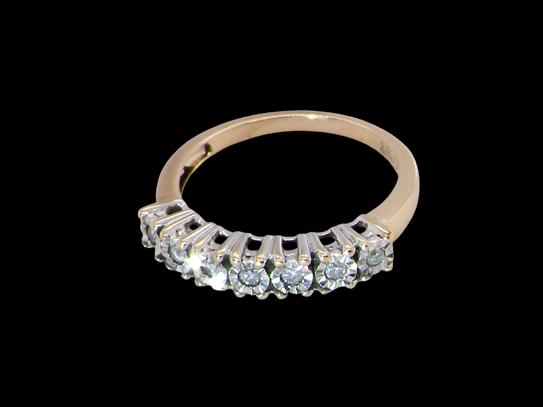 top view 9 carat gold half hoop eternity ring.
Set with seven small white diamonds, each 1.8mm within an illusion setting that is 3.8mm in diameter, and white gold. 
