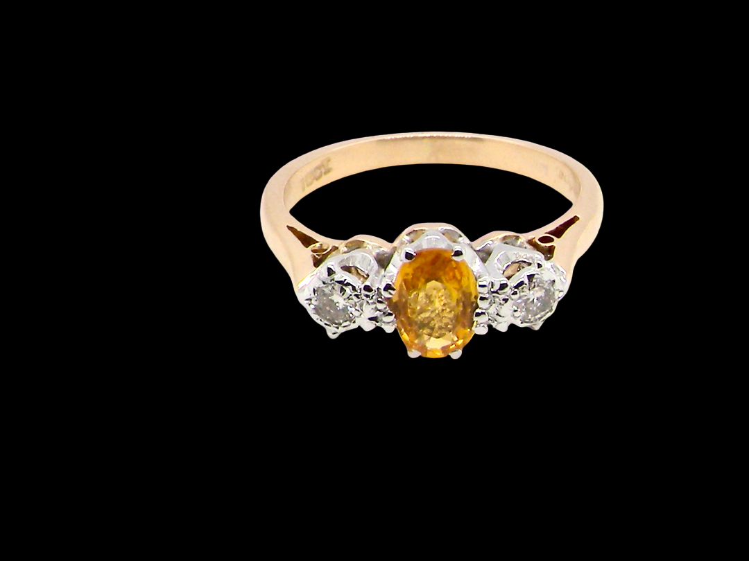 top view A beautiful 18 carat yellow gold trilogy ring, combining the warm golden tones of a yellow sapphire with white diamonds.