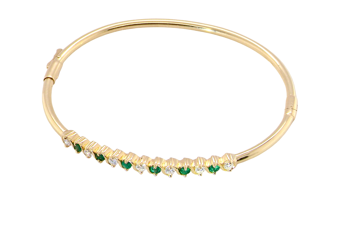 top view A yellow gold bangle. Features alternate emeralds and diamonds. Six 2.7mm emeralds and seven brilliant cut white diamonds, each 2.7mm (total diamond total 0.50 carats)