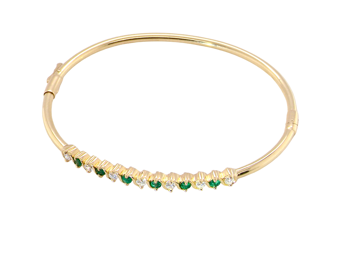 top view A yellow gold bangle. Features alternate emeralds and diamonds. Six 2.7mm emeralds and seven brilliant cut white diamonds, each 2.7mm (total diamond total 0.50 carats)