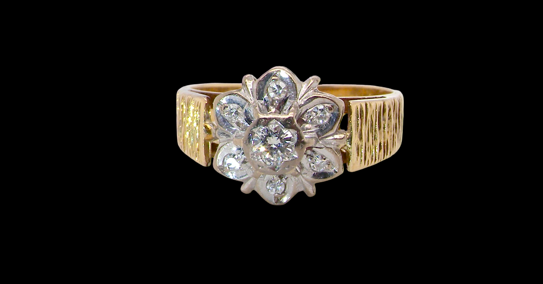 typical design from the 1960s/1970s era, a daisy cluster set with brilliant cut white diamonds and and a bark design finish to both shoulders.