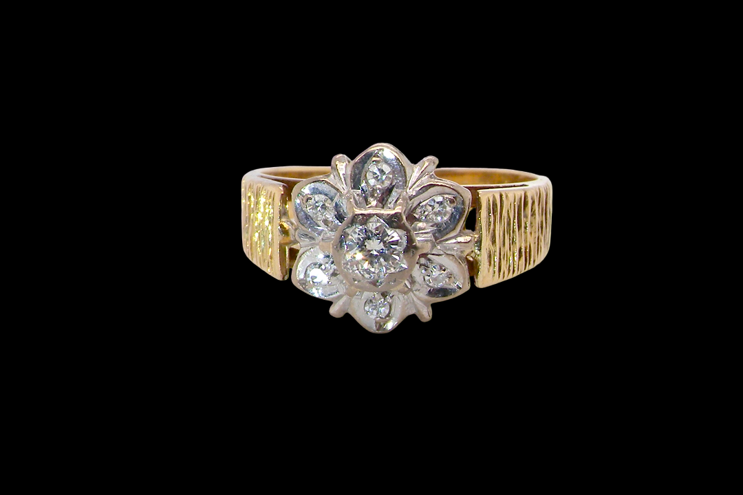 typical design from the 1960s/1970s era, a daisy cluster set with brilliant cut white diamonds and and a bark design finish to both shoulders.