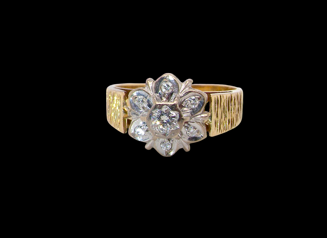 typical design from the 1960s/1970s era, a daisy cluster set with brilliant cut white diamonds and and a bark design finish to both shoulders.