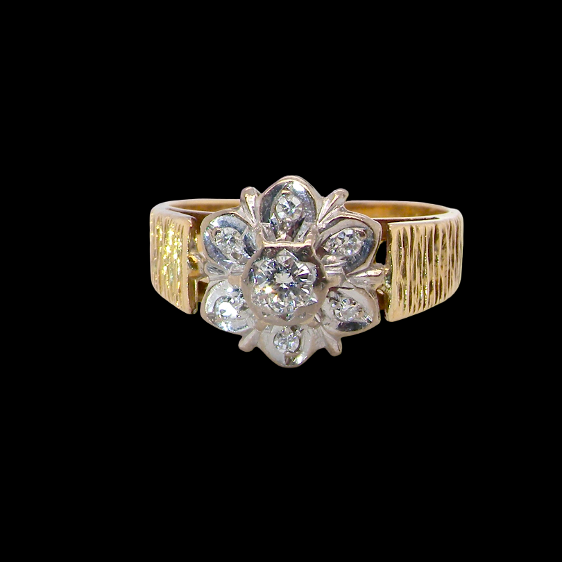 typical design from the 1960s/1970s era, a daisy cluster set with brilliant cut white diamonds and and a bark design finish to both shoulders.