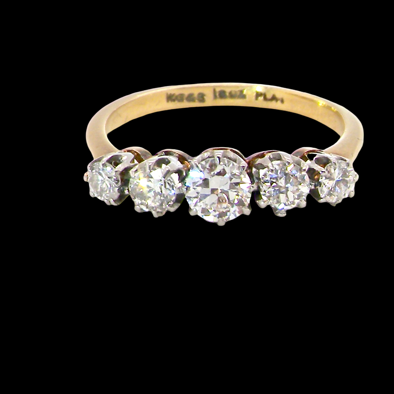 A five-stone diamond ring with a yellow gold band, set against a solid black background. The inner band is engraved with 'MOSES 18.