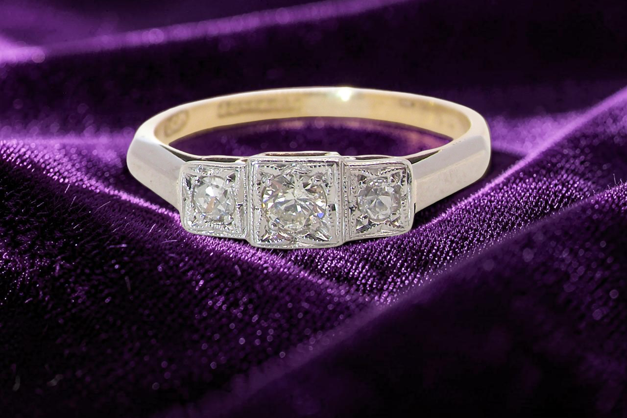 A vintage trilogy ring. Set with three old brilliant cut white diamonds, centre 3mm and each side a 2.4mm diamond. Total estimated at 0.20 carats, colour H-j, clarity Si