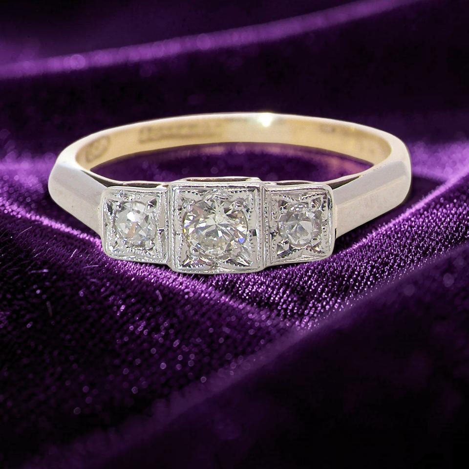 A vintage trilogy ring. Set with three old brilliant cut white diamonds, centre 3mm and each side a 2.4mm diamond. Total estimated at 0.20 carats, colour H-j, clarity Si