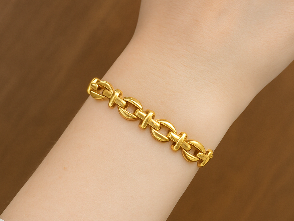 Gold chain bracelet on a wrist against a wooden background