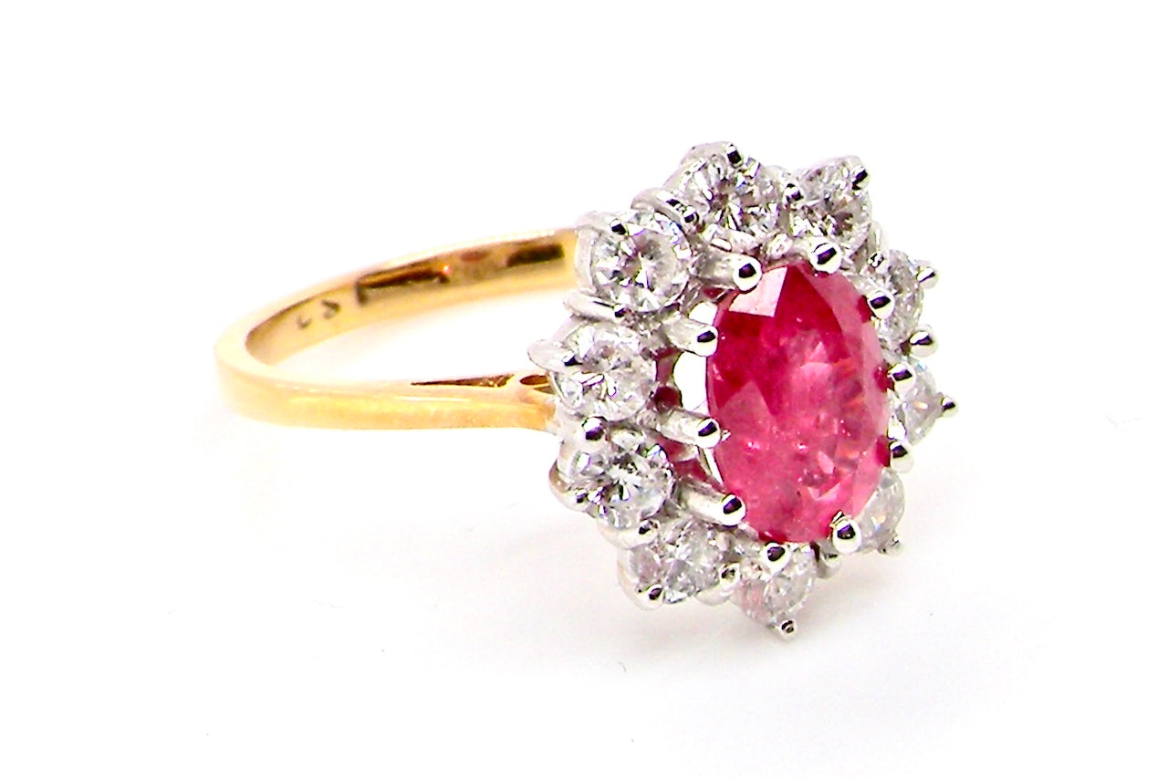 A classic cluster ring centred with an oval pinkish-red ruby measuring approximately 9 × 6 mm (estimated 1.75 carats)