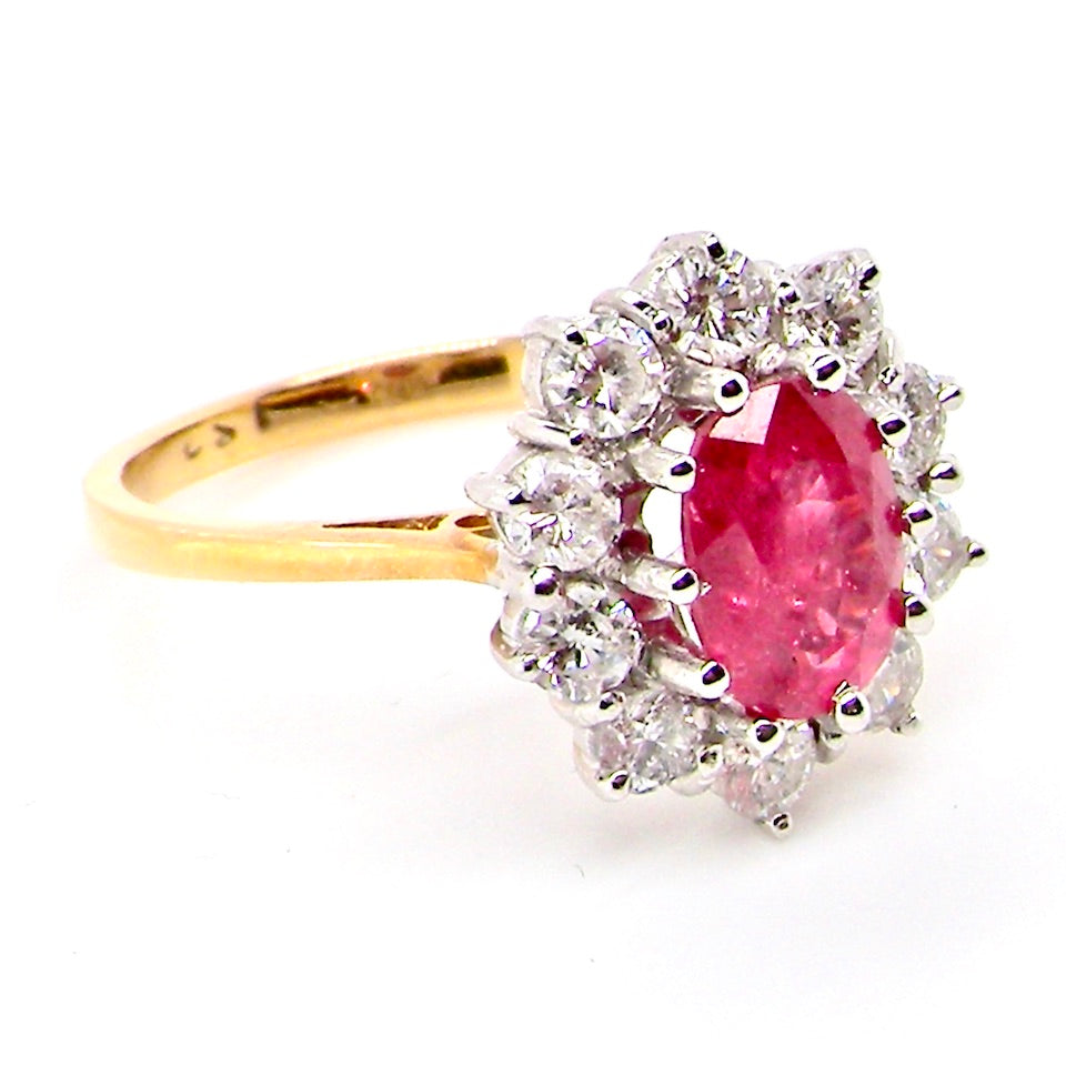 A classic cluster ring centred with an oval pinkish-red ruby measuring approximately 9 × 6 mm (estimated 1.75 carats)
